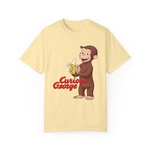 Camiseta unisex de manga corta con colores cómodos y dibujo animado moderno de Jorge el curioso pelando un plátano