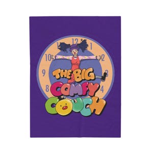 May include: A purple background with a colorful clock featuring a cartoon clown with a red nose and a red dress. The clock face says "The Big Comfy Couch" in colorful letters.