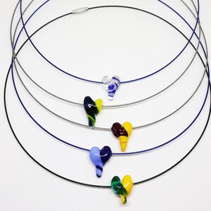 May include: Five necklaces with different colored glass heart pendants. The necklaces are layered on top of each other. The hearts are blue, green, yellow, brown, and clear.