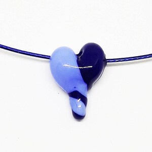 May include: A blue and purple glass heart pendant on a silver chain necklace.