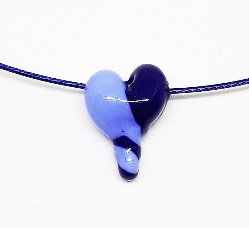 May include: A blue and purple glass heart pendant on a silver chain necklace.