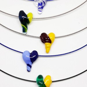 May include: Five necklaces with different colored glass heart pendants. The hearts are all in a swirl pattern and are made of clear, blue, green, yellow, and brown glass.