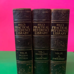 Könnte beinhalten: Drei schwarze, ledergebundene Bücher mit goldenen Lettern. Die Bücher tragen den Titel "Hill's Practical Reference Library" und jedes Band hat ein anderes Thema: "Vol. III. Incense - Python", "Vol. I. Reading Index - A - Caudine Forks" und "Vol. IV. Q - Zymotic Diseases".
