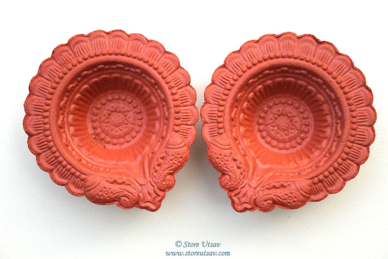 Pode incluir: Duas l&acirc;mpadas a &oacute;leo cor de terracota com intrincados padr&otilde;es florais e geom&eacute;tricos. As l&acirc;mpadas t&ecirc;m uma borda ondulada e um design central. A imagem &eacute; tirada de cima, mostrando os detalhes das l&acirc;mpadas em um fundo branco.
