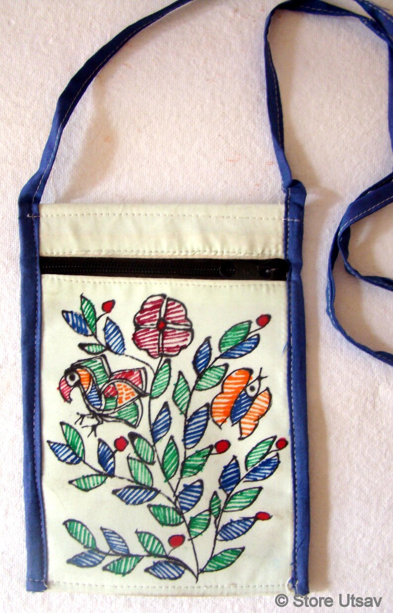 May include: A rectangular off-white fabric crossbody bag with a blue trim and strap. The front features a hand-drawn style illustration of a bird, a flower, and a butterfly in red, green, and blue ink. A black zipper runs across the top section.