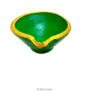 May include: A small, bowl-shaped diya lamp with a vibrant green interior and exterior. The rim is painted with a textured, metallic gold border, and a small spout is visible at the front edge. The text Store Utsav is printed at the bottom.