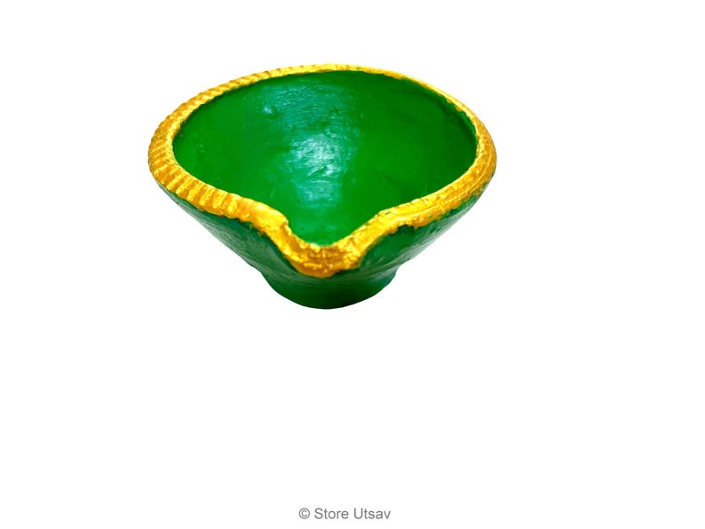 May include: A small, bowl-shaped diya lamp with a vibrant green interior and exterior. The rim is painted with a textured, metallic gold border, and a small spout is visible at the front edge. The text Store Utsav is printed at the bottom.