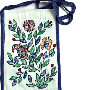 Back side of close up of intricate Mithila folk art brushwork on a handmade mint blue upcycled cotton fabric bag with a blue border and strap. The design includes a bird, a flower, and a butterfly, with green, blue, orange, and red accents. The bag is rectangular and has a strap for carrying.