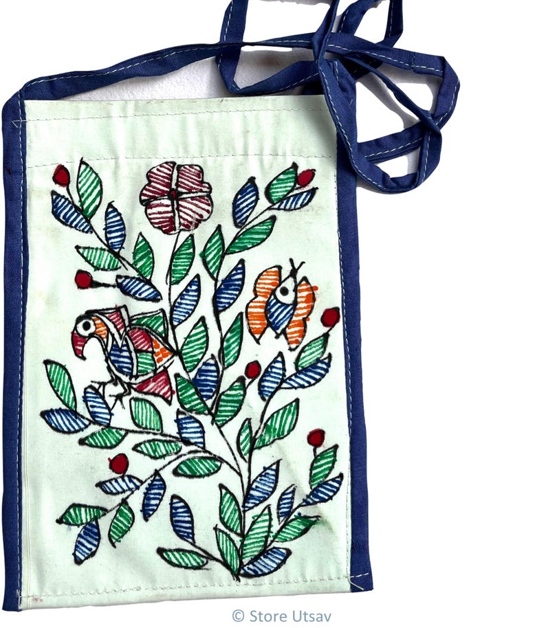 Back side of close up of intricate Mithila folk art brushwork on a handmade mint blue upcycled cotton fabric bag with a blue border and strap. The design includes a bird, a flower, and a butterfly, with green, blue, orange, and red accents. The bag is rectangular and has a strap for carrying.