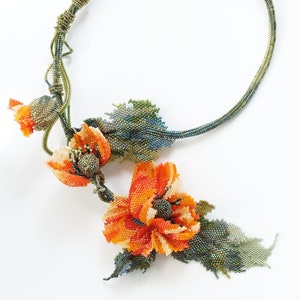 Könnte beinhalten: Eine Perlenkette mit einem zarten Design mit zwei orangefarbenen Mohnblumen und grünen Blättern.
