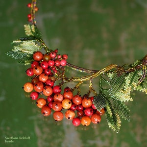 May include: A beaded necklace with a branch design and red and orange berries. The necklace is made with small beads and has a delicate, intricate design.