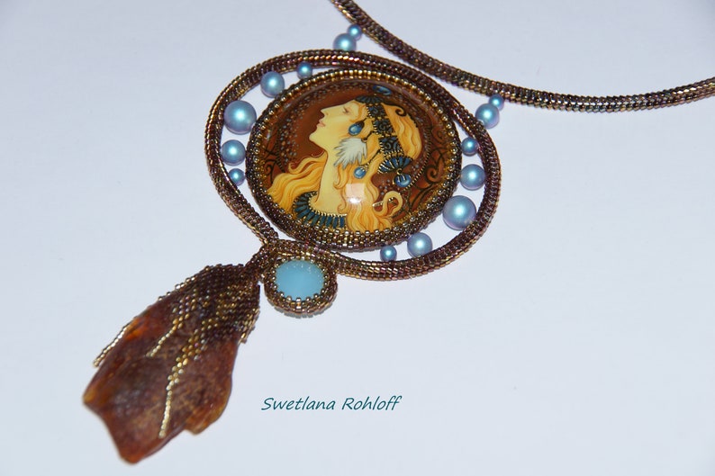 May include: A beaded necklace with a round pendant featuring a painted portrait of a woman with long blonde hair. The pendant is surrounded by blue beads and the necklace is made of brown beads.