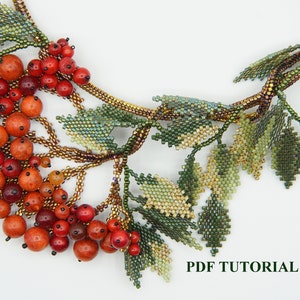 May include: A beaded necklace with a cluster of red and orange beads, resembling berries, and green leaves. The necklace is made with seed beads and features a delicate, intricate design. The text "PDF TUTORIAL" is visible at the bottom of the image.