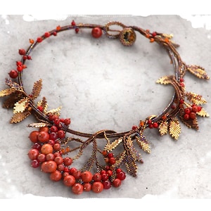 May include: A beaded necklace with a design of leaves and berries. The leaves are gold and brown, and the berries are red.