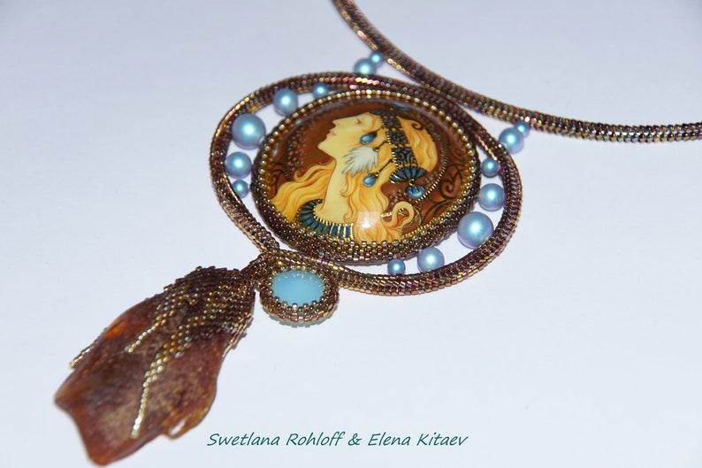 May include: A beaded necklace with a large, round pendant featuring a painted portrait of a woman with long blonde hair. The pendant is surrounded by smaller blue beads and the necklace is made of brown and gold beads.