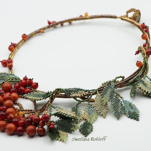 May include: A beaded necklace with a design of leaves and red berries. The necklace is made with brown, green, and red beads. The necklace is on a white background. "Svetlana Rohloff" is written in the bottom right corner of the image.