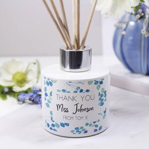 May include: White diffuser bottle with a silver lid and blue and green floral design. The bottle has the text "Thank You Miss Johnson From Tom X" printed on the front.