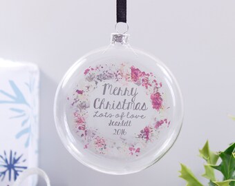 May include: Clear glass Christmas ornament with a floral design and the text "Merry Christmas Lots of love Scarlett 2016".