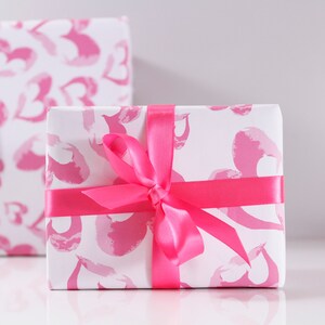 May include: A white gift box with a pink and white heart pattern wrapped with a pink satin ribbon.