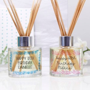 May include: Two clear glass diffuser bottles with silver lids and wooden sticks. The bottles have personalized labels with the text "Happy 18th Birthday Danielle" and "Happy 60th Birthday Nanna!"