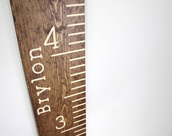 May include: A brown wooden growth chart with white markings and the name "BYLON" and the numbers "3" and "4" printed on it.