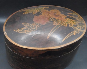 May include: A round wooden box with a black lacquered finish. The lid is decorated with a floral design in gold and red paint.
