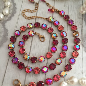 May include: A gold chain necklace with a double row of red, orange, and pink iridescent crystal beads.