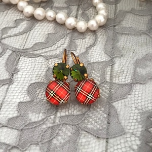 May include: A pair of dangle earrings with a red and black plaid pattern and a green gemstone accent.