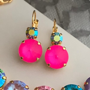 Peut inclure: Un ensemble de bijoux comprenant un bracelet et des boucles d'oreilles. Le bracelet est en métal doré et comporte une série de cristaux ronds colorés. Les boucles d'oreilles sont également dorées et présentent un seul cristal rond.