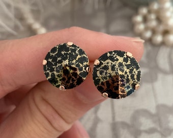 Pode incluir: Um par de brincos redondos, pretos e dourados com um design de estampa de leopardo.