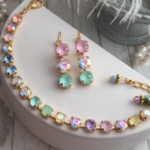 May include: A set of pastel-colored crystal earrings and a bracelet. The earrings are made of three crystals each, in shades of pink, light blue, and green. The bracelet is made of a chain of crystals in a rainbow of colors, including pink, light blue, green, yellow, and purple.