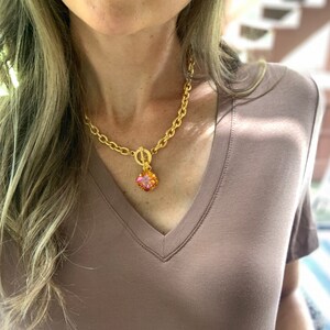 Pode incluir: Um colar de corrente de ouro com um pingente quadrado de pedra preciosa rosa e laranja.