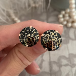 May include: A pair of gold-tone stud earrings with a black and gold leopard print design.