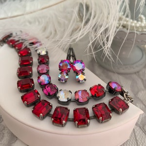 May include: A set of red crystal earrings and a necklace with a silver chain. The necklace has a variety of red crystal shapes.
