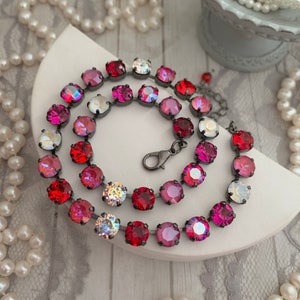 May include: A multi-coloured crystal necklace with a gradient of red, pink, and clear crystals. The necklace is made of small round crystals connected by a silver chain.