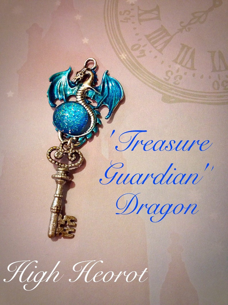 May include: A silver-colored key pendant with a blue dragon design. The dragon has blue wings and is perched above a blue glittery orb. The text on the image reads "Treasure Guardian Dragon" and "High Heorot".