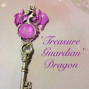 May include: A silver-colored key pendant with a purple dragon charm and a round, translucent purple bead. The dragon has outstretched wings and is attached to the key. The text on the image reads "Treasure Guardian Dragon" and "High Heorot".