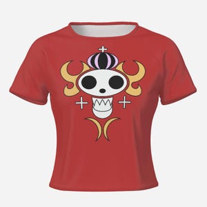 May include: Red short-sleeved t-shirt with a white skull design, black eyes, a crown, and gold details. The design includes crosses and curved shapes. The shirt is a solid red colour.