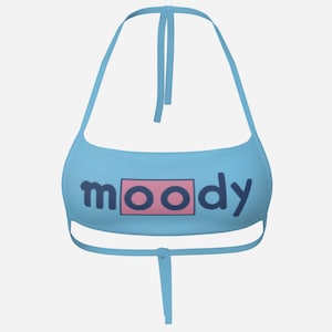 Puede incluir: Top halter azul claro con la palabra "moody" en letras azul oscuro dentro de un rectángulo rosa. El top tiene finas correas que se atan al cuello y a la espalda.