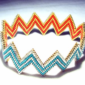 Op de afbeelding: Een kralen armband met een zigzagpatroon in turquoise, zilver en oranje.