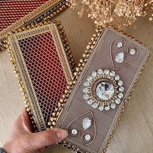 Può includere: Tre scatole decorative con intricate lavorazioni in metallo dorato e accenti di gioielli. Le scatole sono rivestite in tessuto rosso e marrone e decorate con strass e motivi a forma di cuore.