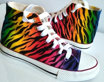 May include: A pair of high-top canvas shoes with a rainbow tiger stripe pattern. The shoes have white laces and a white rubber sole.