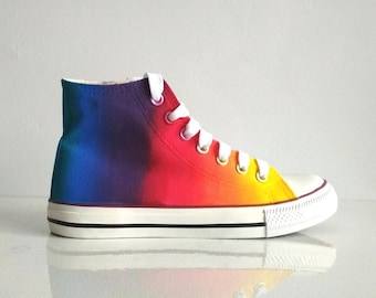 May include: High-top canvas trainers with a rainbow ombre design. The shoes are white with a black trim and a white rubber sole.