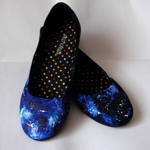 K&ouml;nnte beinhalten: Ein Paar blaue Canvas-Ballerinas mit Galaxie-Druck. Das Innere der Schuhe ist schwarz mit wei&szlig;en Punkten und der Text "Senses" ist auf der Innensohle gedruckt.