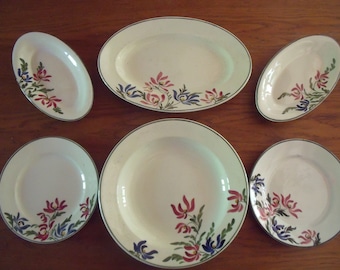 May include: Set of six white ceramic plates with green trim and floral designs in shades of pink, blue, and green.
