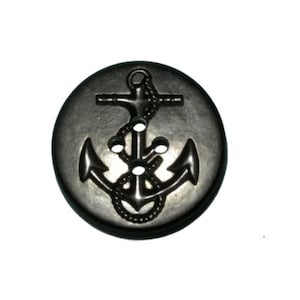 May include: A round, dark gray button with a raised anchor design. The anchor features a rope, a crossbar, and two flukes. The button has three holes for sewing and is set against a white background.
