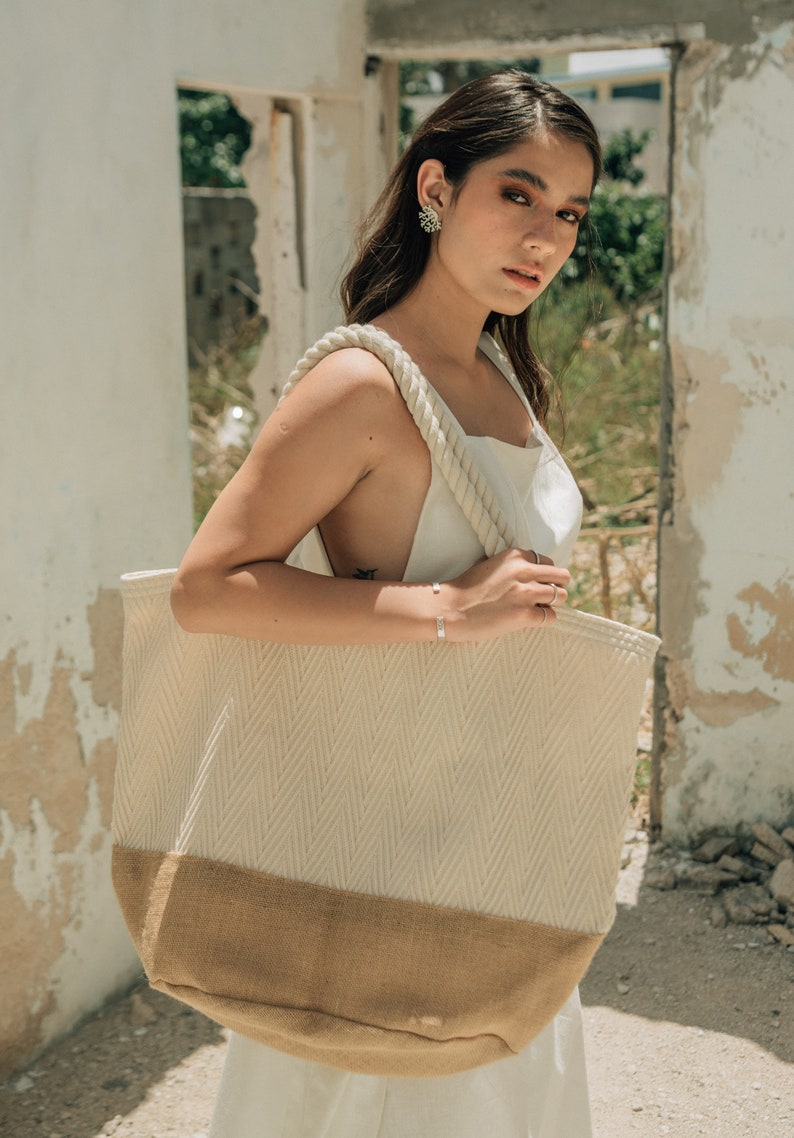 Puede incluir: Una bolsa de lona blanca y marr&oacute;n con asas de cuerda. La bolsa tiene un patr&oacute;n de chevron en la mitad superior y un fondo marr&oacute;n s&oacute;lido.