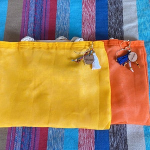 May include: Two fabric bags with drawstrings, one yellow and one orange. Both bags have wooden tags with the word "Summer" written on them.