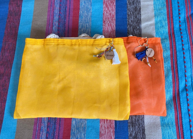May include: Two fabric bags with drawstrings, one yellow and one orange. Both bags have wooden tags with the word "Summer" written on them.