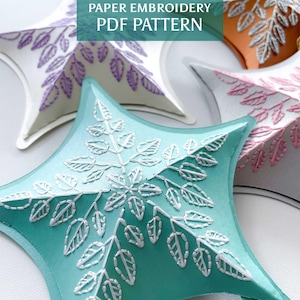 Peut inclure: Gros plan sur des étoiles en papier de différentes couleurs, dont le turquoise, le blanc et l'orange. Chaque étoile présente un motif de feuilles détaillé en fil blanc. Le texte "PAPER EMBROIDERY PDF PATTERN" est visible.